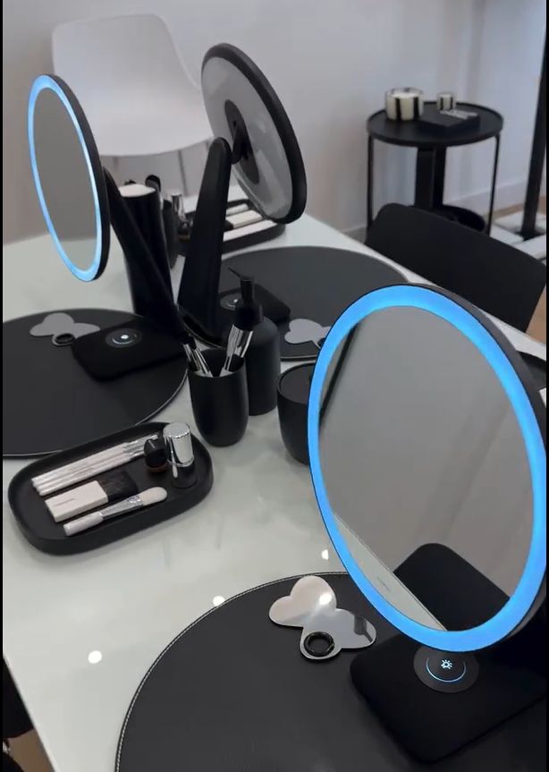 Mesa de trabajo con espejos iluminados, pinceles y productos de maquillaje